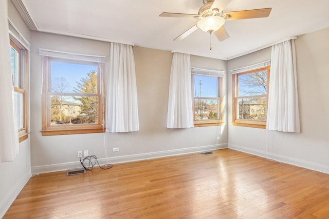spare room with ceiling fan, baseboards, visible vents, and wood finished floors