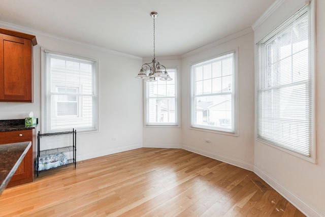unfurnished dining area with baseboards, an inviting chandelier, ornamental molding, and light wood-type flooring