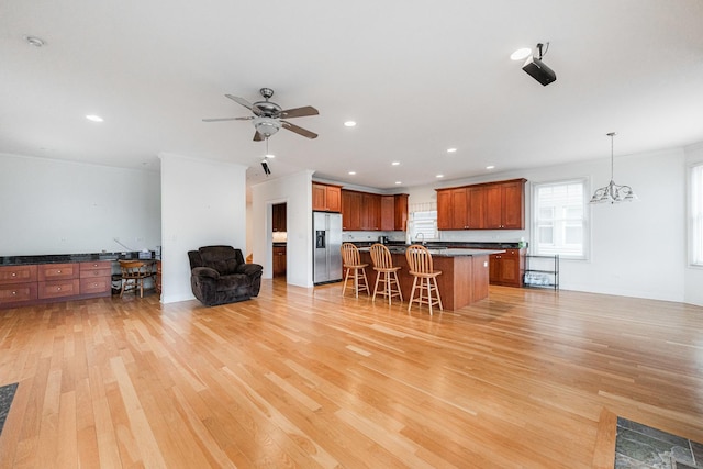 kitchen featuring dark countertops, open floor plan, a breakfast bar area, stainless steel fridge, and light wood finished floors
