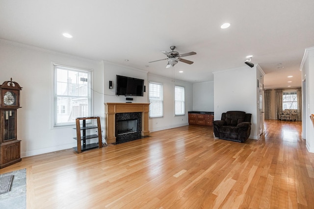 unfurnished living room featuring crown molding, a high end fireplace, ceiling fan, and light wood-type flooring