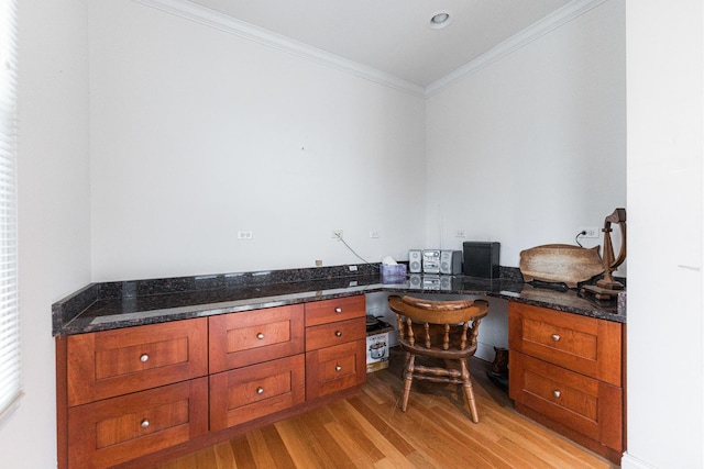 office space with built in study area, crown molding, and light wood finished floors