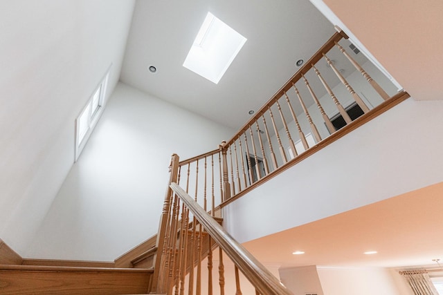stairway with recessed lighting, a high ceiling, and a skylight