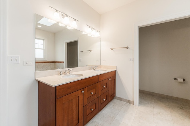 bathroom with double vanity, a sink, and baseboards
