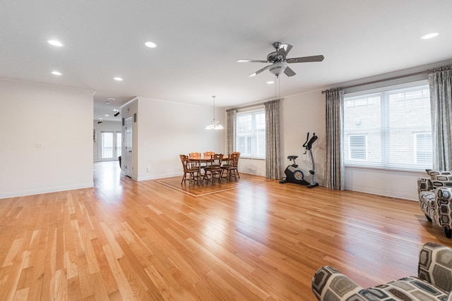 living area with recessed lighting, baseboards, light wood finished floors, and ceiling fan with notable chandelier