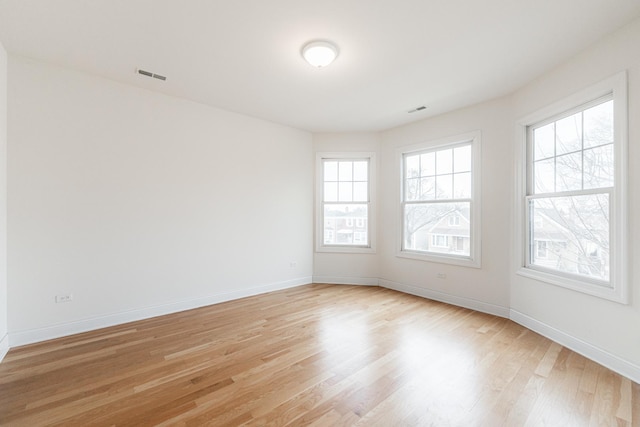 unfurnished room with baseboards, visible vents, and light wood-style floors