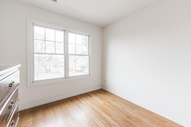 spare room with baseboards, light wood-style flooring, and a wealth of natural light