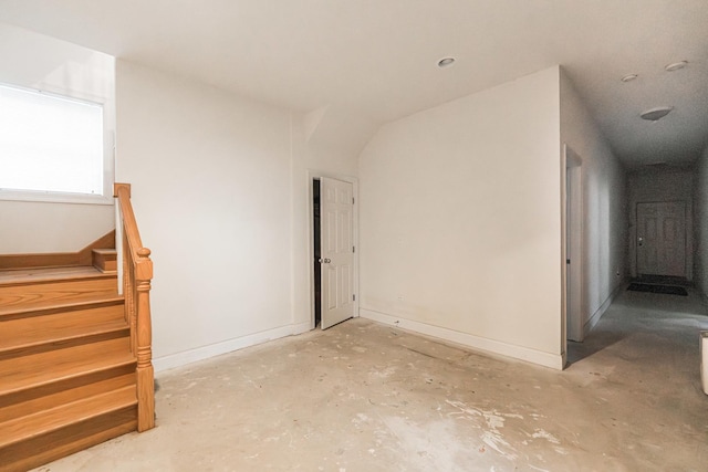interior space with baseboards, unfinished concrete flooring, and stairs