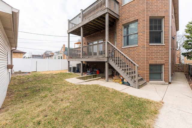rear view of property with a lawn, a fenced backyard, central AC, and brick siding