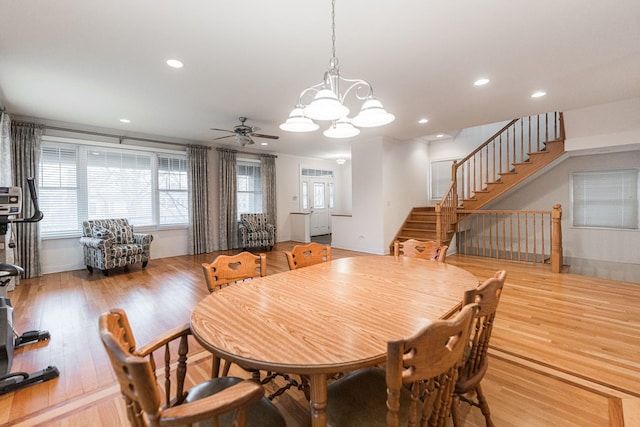 dining space with recessed lighting, light wood-style flooring, ceiling fan with notable chandelier, and stairway