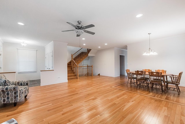 living room with ceiling fan, light wood-style floors, recessed lighting, ornamental molding, and stairway