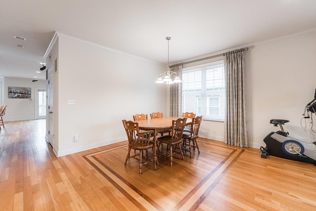 dining room with crown molding, baseboards, and light wood-style floors