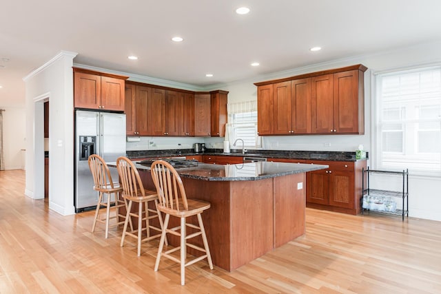 kitchen featuring light wood-style floors, stainless steel fridge, ornamental molding, and a center island