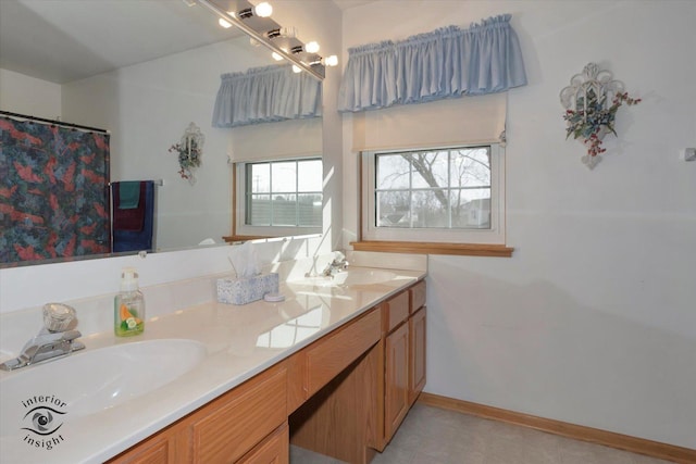 bathroom with a sink, baseboards, tile patterned flooring, and double vanity