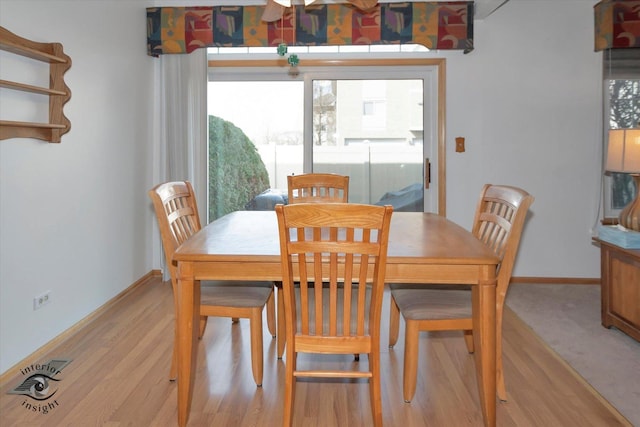 dining space with light wood-type flooring and baseboards