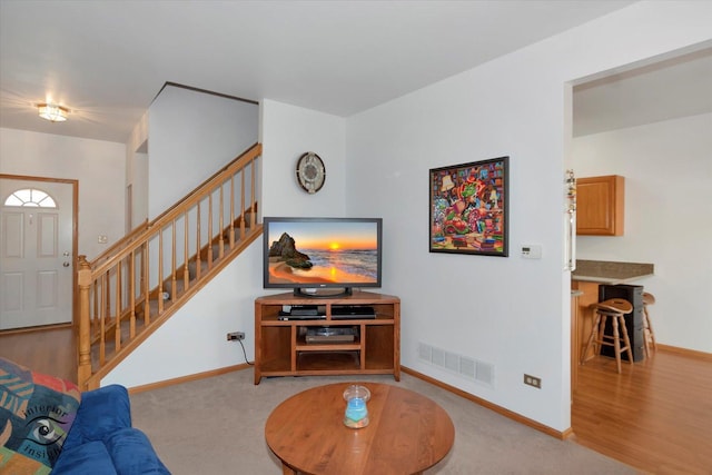 carpeted living room with visible vents, stairs, and baseboards