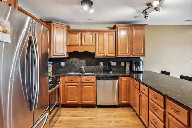 5652 W 63rd St Unit 3E, Chicago, IL 60638 - kitchen featuring appliances with stainless steel finishes, a sink, brown cabinetry, light wood-style flooring, and backsplash