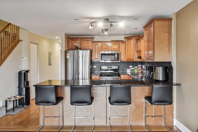 5652 W 63rd St Unit 3E, Chicago, IL 60638 - kitchen featuring appliances with stainless steel finishes, brown cabinetry, a peninsula, baseboards, and decorative backsplash