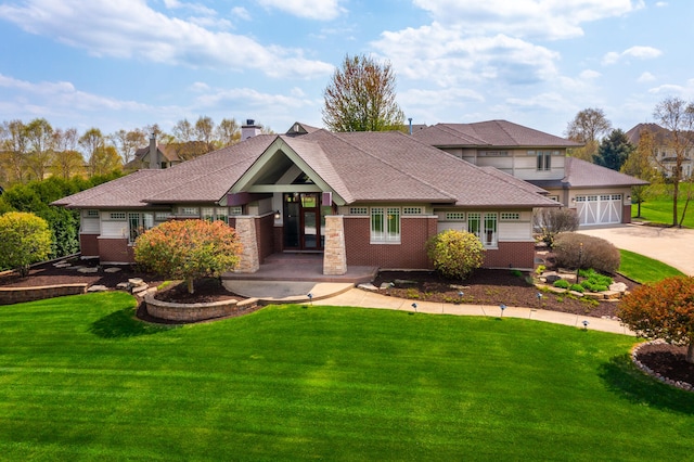 view of front facade featuring brick siding, roof with shingles, driveway, and a front yard