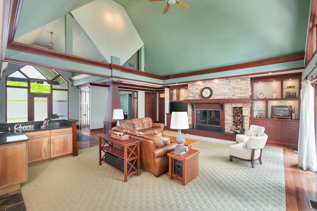 living room featuring high vaulted ceiling, a stone fireplace, a ceiling fan, and wood finished floors