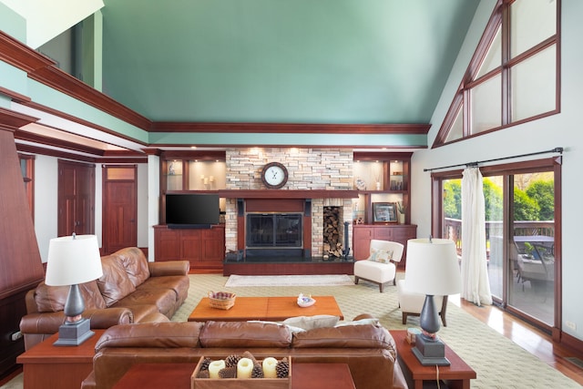 living area with high vaulted ceiling, a stone fireplace, and wood finished floors