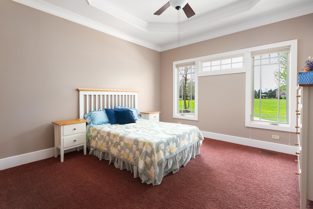 carpeted bedroom featuring crown molding, multiple windows, a tray ceiling, and visible vents