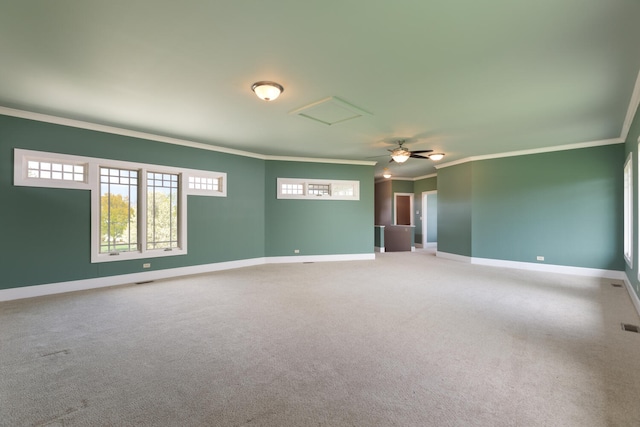 spare room featuring a ceiling fan, attic access, crown molding, baseboards, and carpet floors