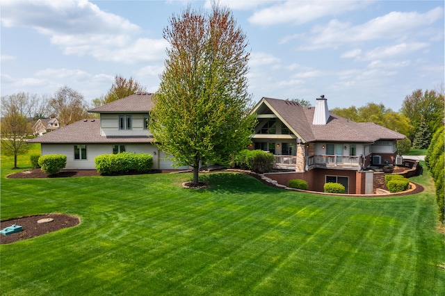 rear view of house with a lawn, a balcony, and a chimney