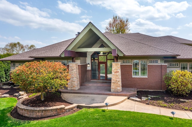 view of front of house with a shingled roof and brick siding