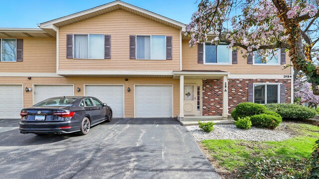 townhome / multi-family property featuring an attached garage, driveway, and brick siding
