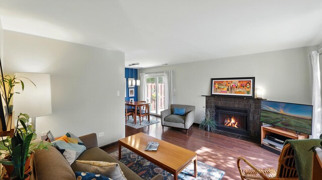 living area featuring a warm lit fireplace and wood finished floors