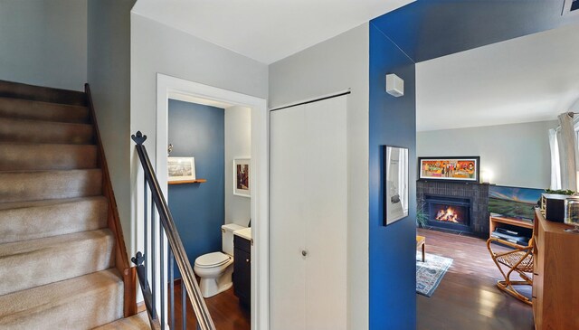 stairs featuring a lit fireplace, wood finished floors, and visible vents