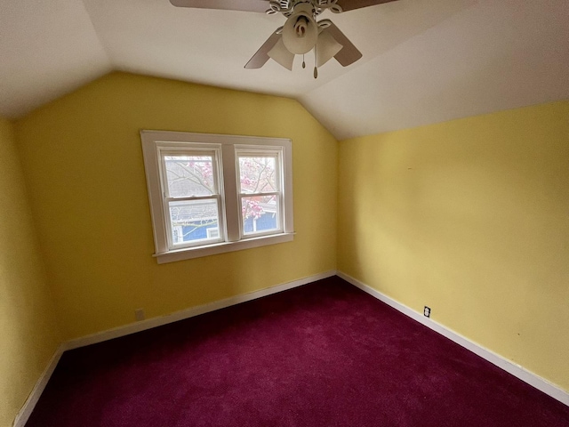 additional living space with baseboards, a ceiling fan, vaulted ceiling, and dark colored carpet
