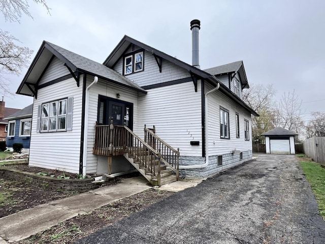 bungalow with a detached garage, driveway, a shingled roof, and an outdoor structure