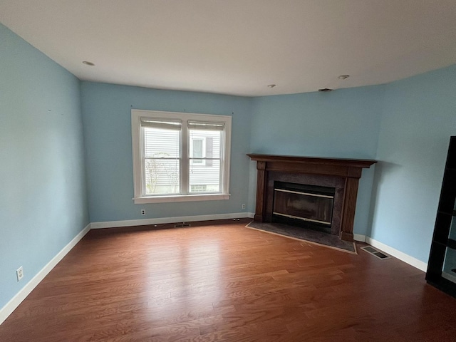 unfurnished living room with baseboards, a fireplace with flush hearth, and wood finished floors