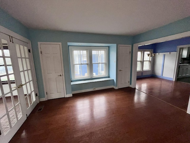 interior space with french doors, baseboards, wood finished floors, and visible vents
