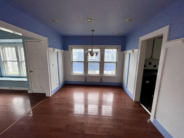 unfurnished dining area featuring baseboards, an inviting chandelier, and plenty of natural light