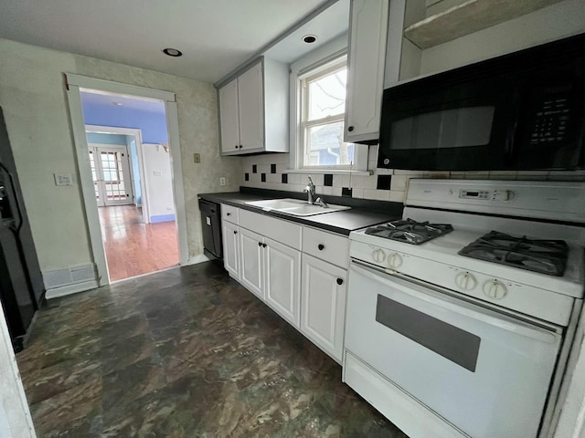 kitchen with a sink, black appliances, dark countertops, and a healthy amount of sunlight