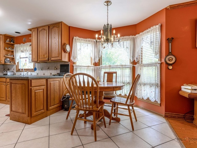 dining area featuring a chandelier, light tile patterned flooring, and baseboards