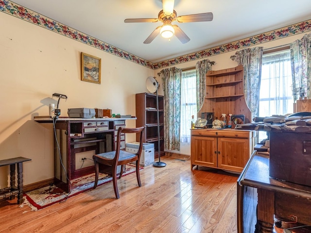 home office featuring light wood-style floors, a ceiling fan, and baseboards