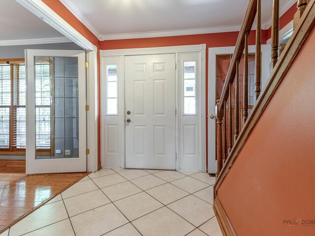 foyer entrance with stairway, crown molding, and light tile patterned floors