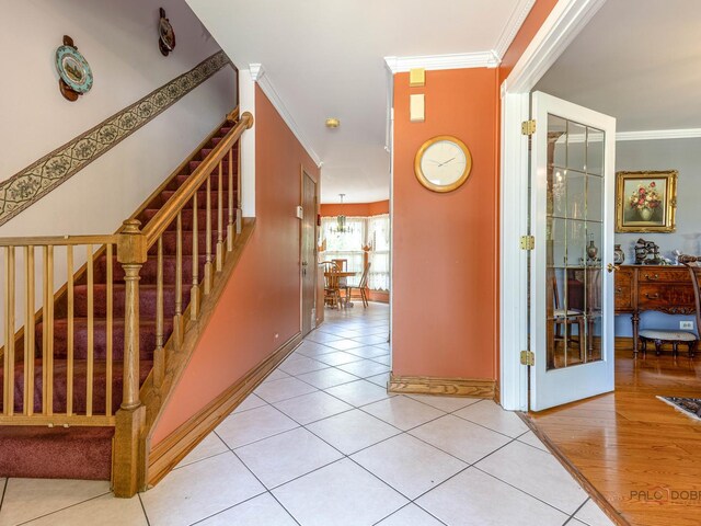 hall with ornamental molding, light tile patterned floors, stairs, and baseboards