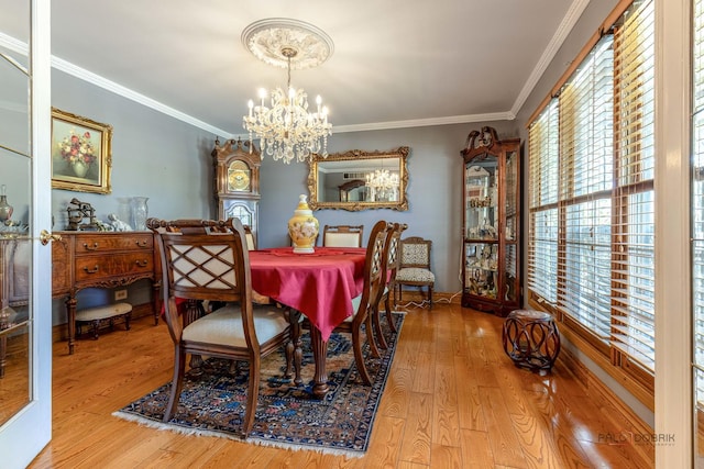 dining area with a chandelier, wood finished floors, ornamental molding, and baseboards