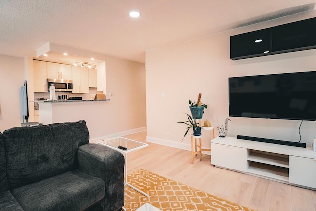 living room featuring recessed lighting, baseboards, and light wood-type flooring