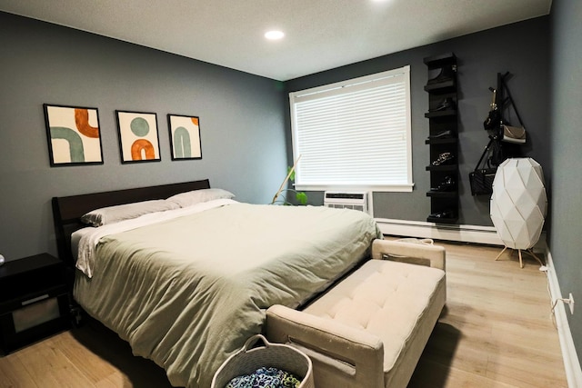 bedroom with recessed lighting, baseboards, a baseboard heating unit, and wood finished floors