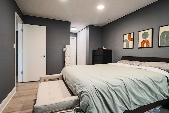 bedroom with baseboards, recessed lighting, light wood finished floors, and a closet