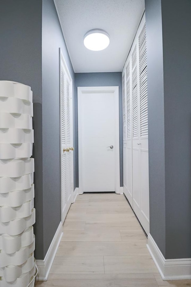 corridor with baseboards and light wood finished floors
