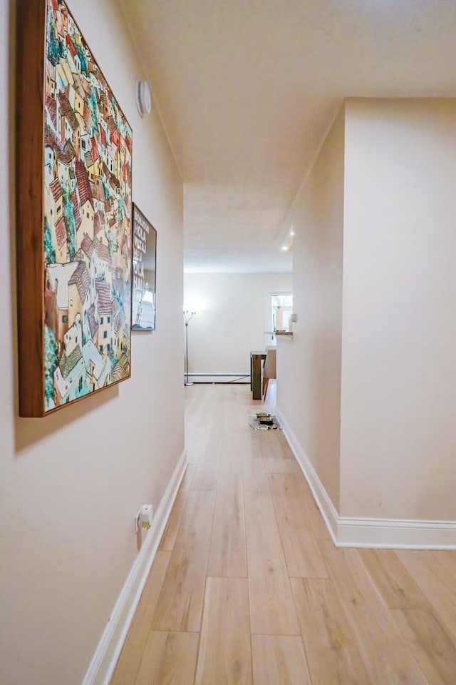 hall with baseboards, a baseboard radiator, and wood finished floors