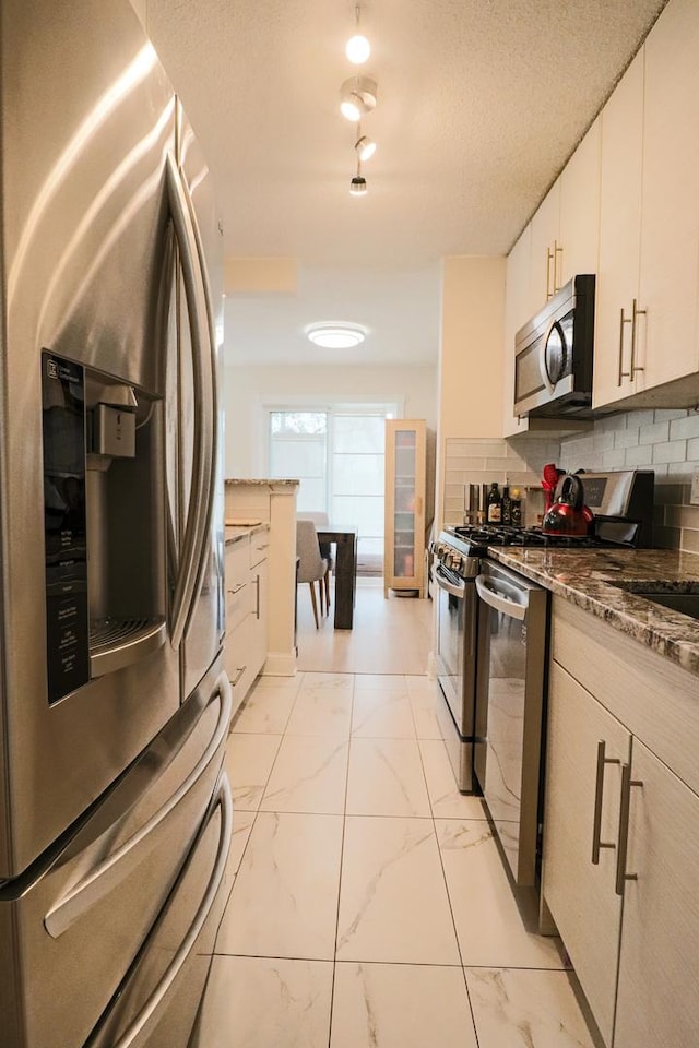 kitchen with decorative backsplash, stainless steel appliances, white cabinetry, and marble finish floor