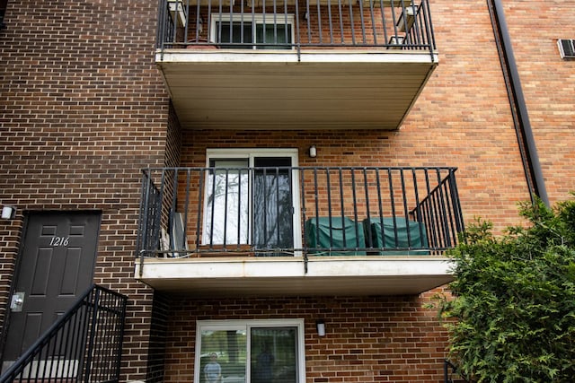 view of property exterior with brick siding and a balcony