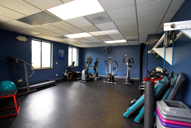 exercise room featuring baseboards and a paneled ceiling